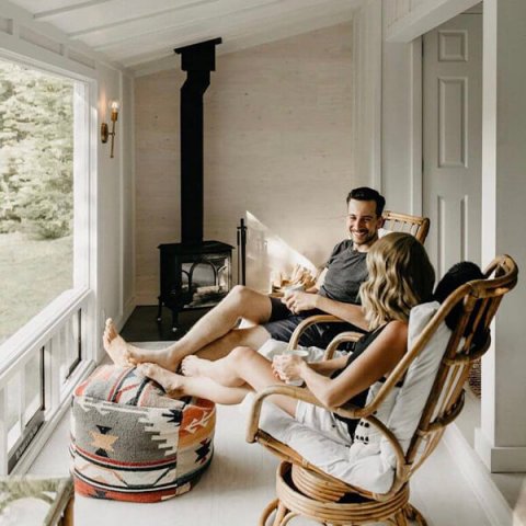 @monettbay kvinna och man som sitter i stolar vid vedspisen Jøtul F 100.