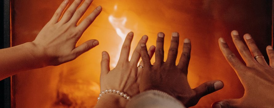 Hender som varmer seg på peisen