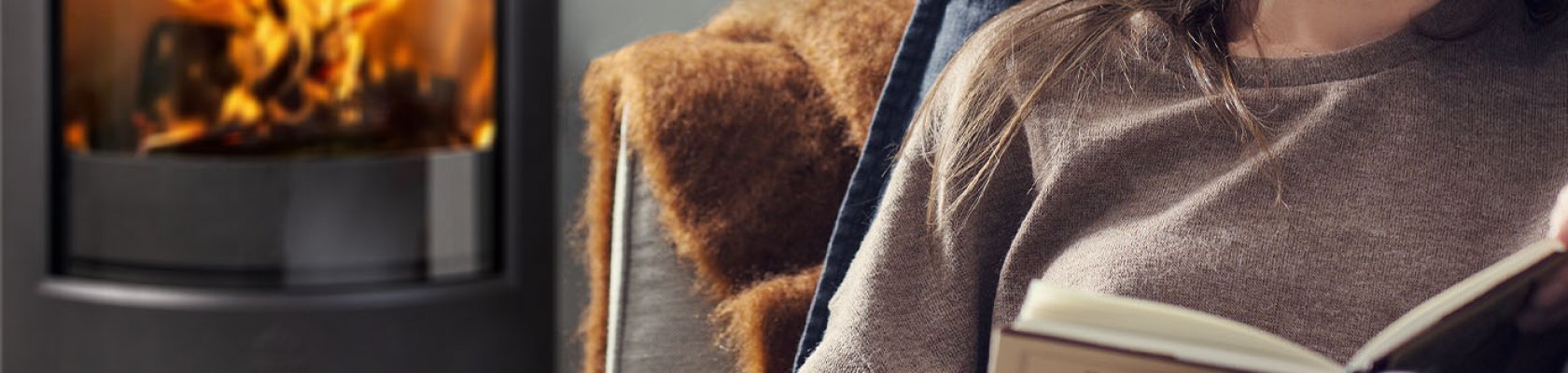 Damen sitter framför vedspisen Jøtul F 373 Advance