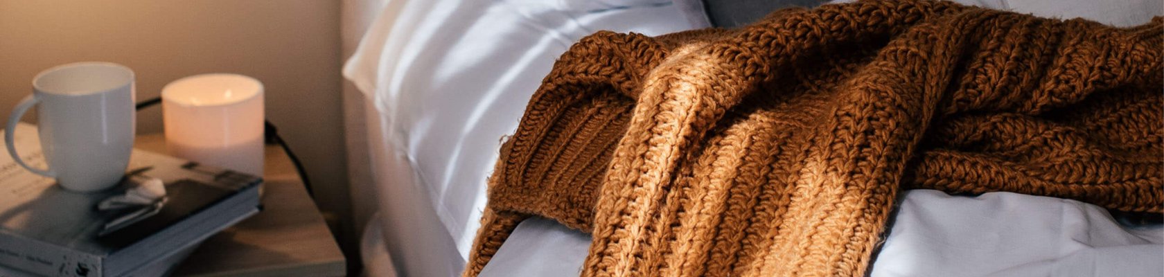 Säng med vitt linne och brun filt