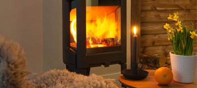 Jøtul F 163 svart kamin med påskliljor i en stuga
