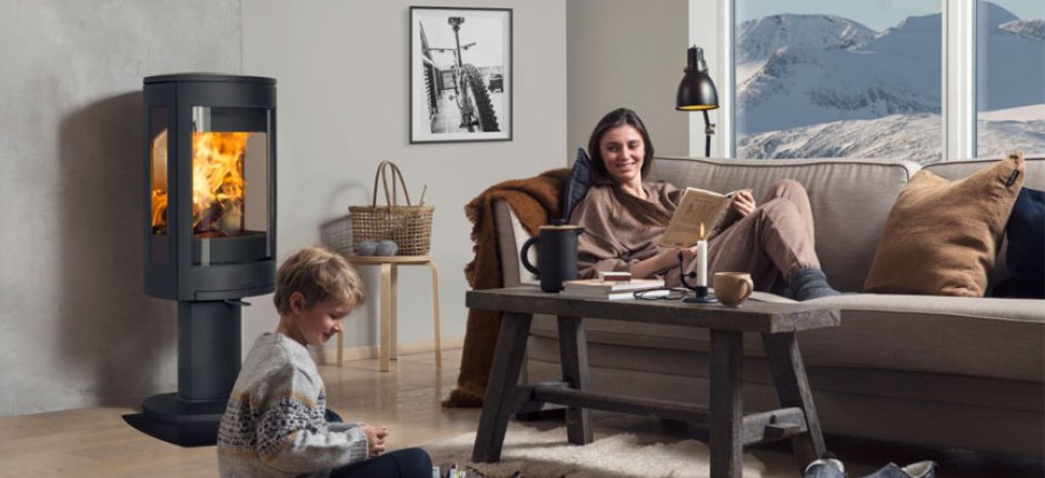 Moder och son framför öppen spis i vardagsrummet. Foto.