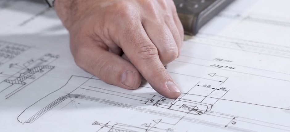 Hand som pekar på processritningar for Jøtul