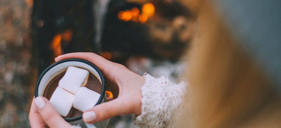 Flicka som dricker kakao vid elden