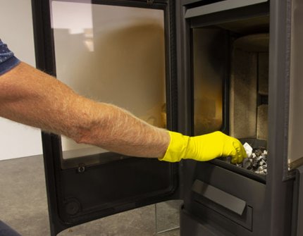 Man som rengör vedspisen Jøtul F 233 med aska och vatten