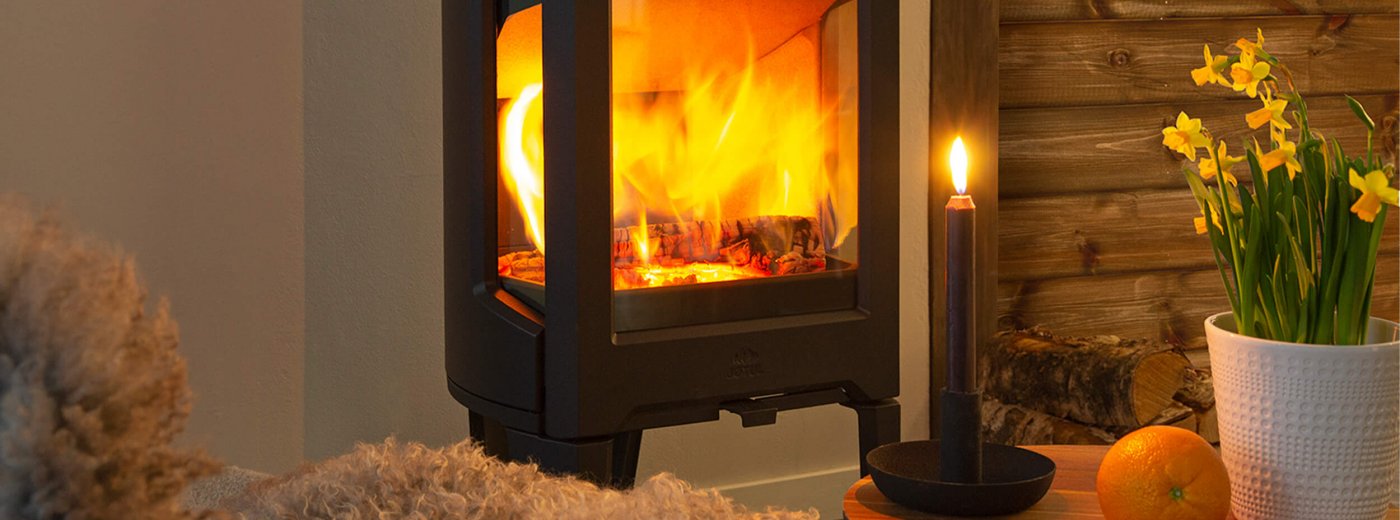 Jøtul F 163 svart kamin med påskliljor i en stuga
