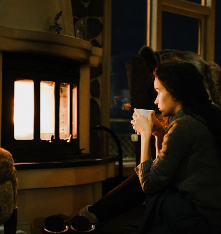 Damen sitter framför den öppna spisen på kvällen